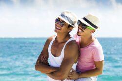 2 gay men holding each other on beach travelling to LGBT friendly holiday destinations