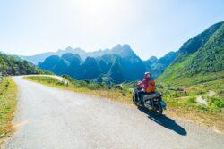 Man riding bike during motorbike holidays in Vietnam along road with mountains in distance